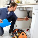 plumber with tools unclogging drain