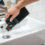 person pouring liquid drain cleaner in sink